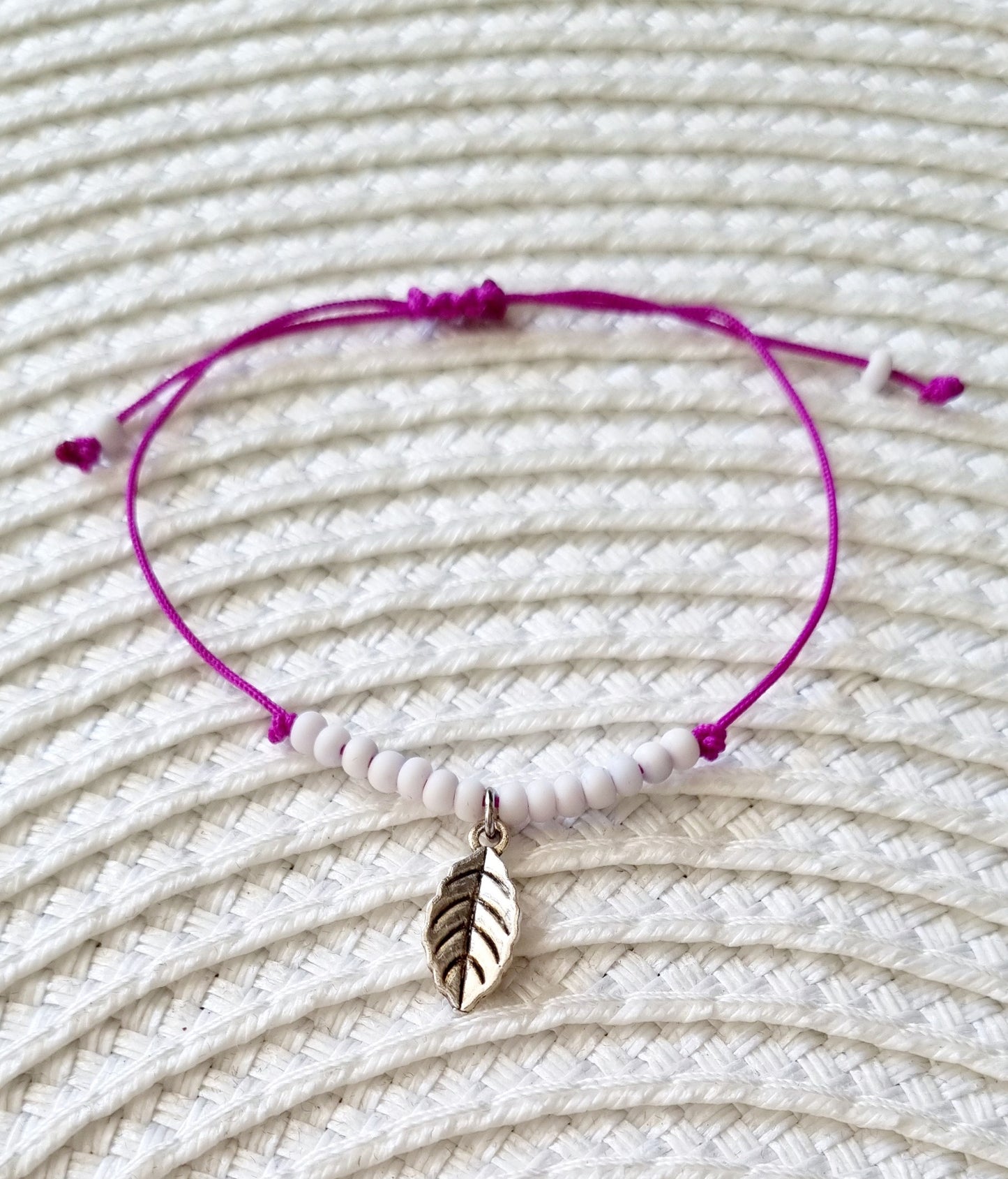 Pulsera realizada con hilo morado, con cierre de macramé y mini bolas de rocalla en tono blanco roto mate. Póntela en la muñeca izquierda para atraer energía positiva a tu vida.
