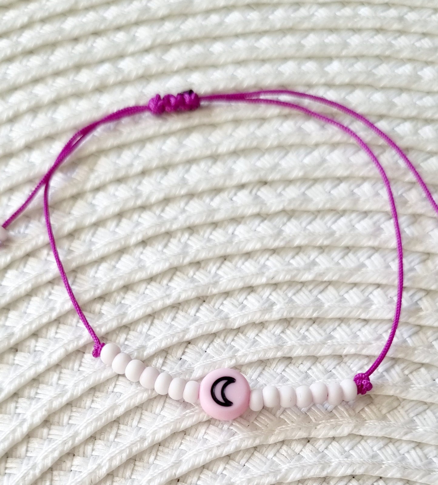Pulsera realizada con hilo morado, con cierre de macramé y mini bolas de rocalla en tono blanco roto mate. Póntela en la muñeca izquierda para atraer energía positiva a tu vida.