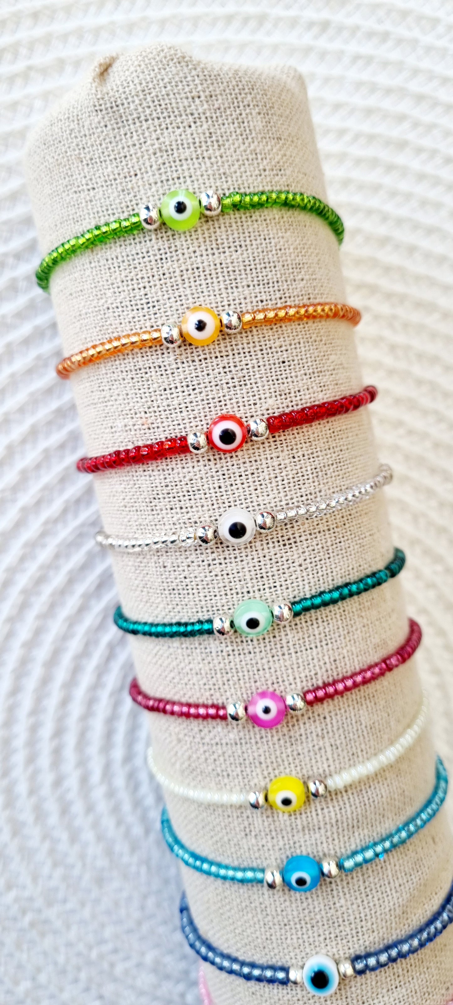 Pulsera elástica de protección ojo turco mini. Realizada con mini bolas de rocalla en tonos brillantes, entre piezas de acero y detalle de ojo turco en distintos colores.