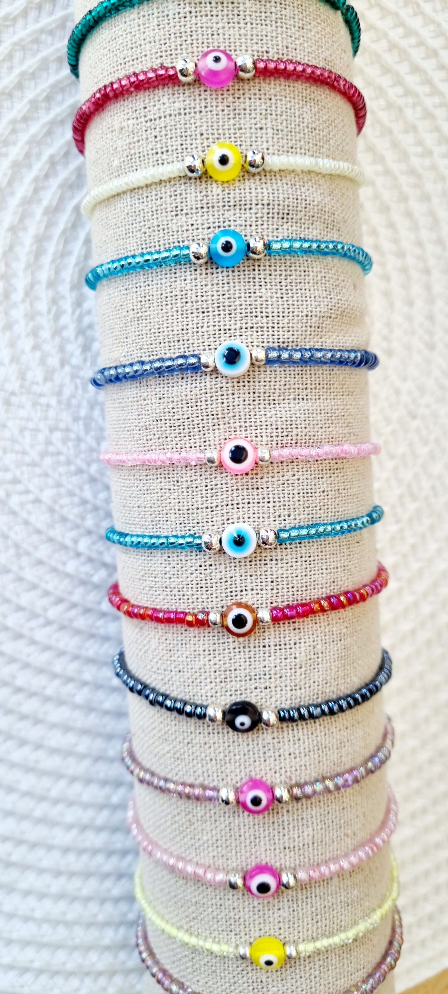 Pulsera elástica de protección ojo turco mini. Realizada con mini bolas de rocalla en tonos brillantes, entre piezas de acero y detalle de ojo turco en distintos colores.