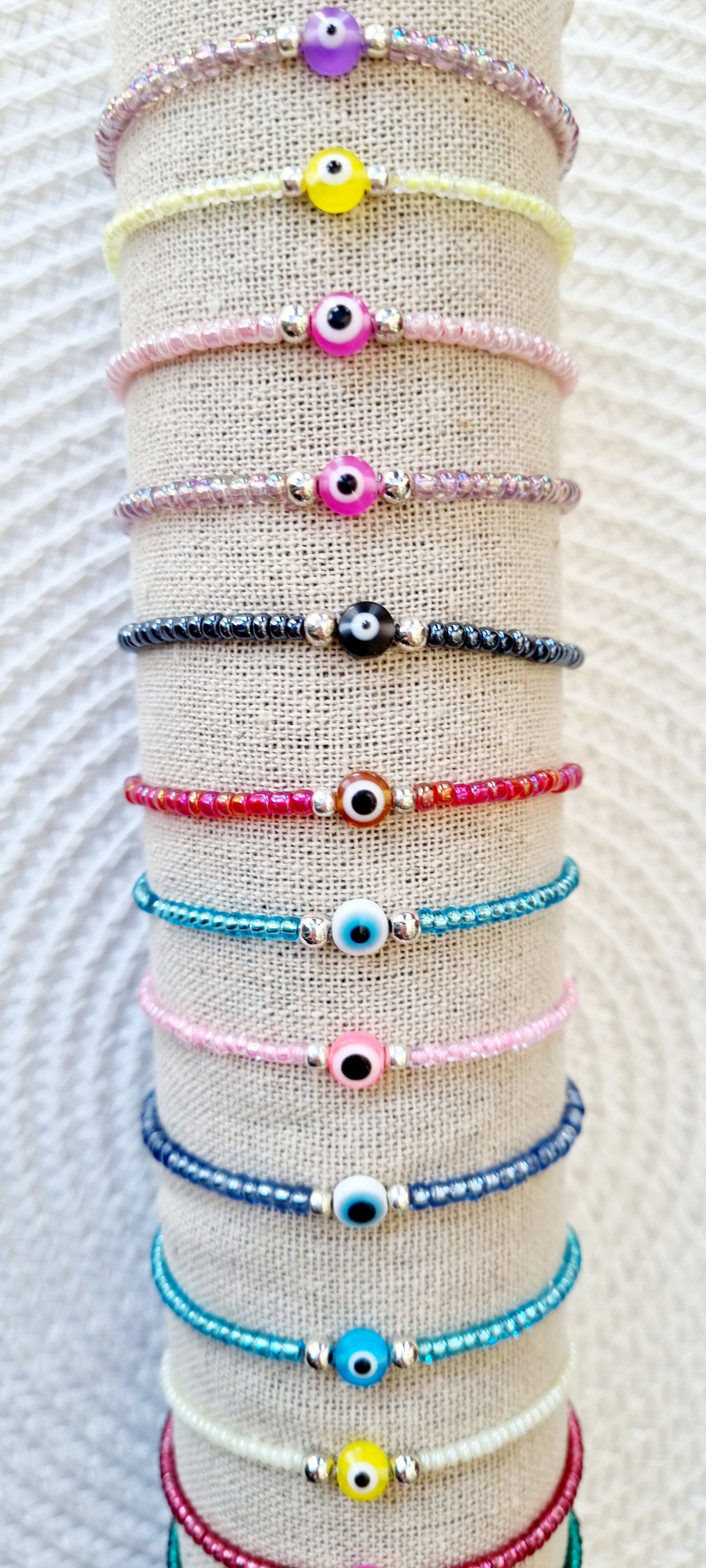 Pulsera elástica de protección ojo turco mini. Realizada con mini bolas de rocalla en tonos brillantes, entre piezas de acero y detalle de ojo turco en distintos colores.