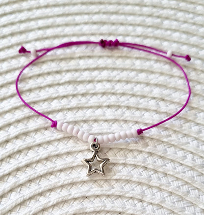 Pulsera realizada con hilo morado, con cierre de macramé y mini bolas de rocalla en tono blanco roto mate.   Póntela en la muñeca izquierda para atraer energía positiva a tu vida.