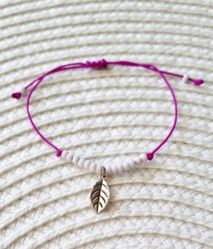 Pulsera realizada con hilo morado, con cierre de macramé y mini bolas de rocalla en tono blanco roto mate.   Póntela en la muñeca izquierda para atraer energía positiva a tu vida.