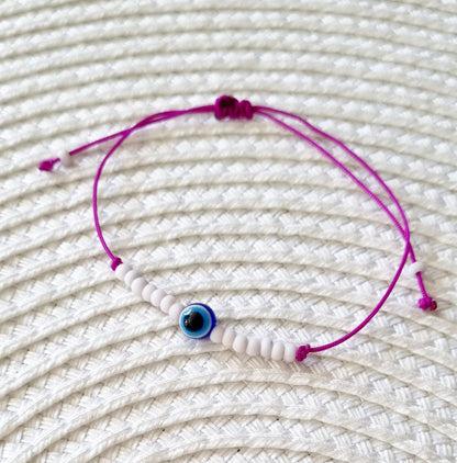 Pulsera realizada con hilo morado, con cierre de macramé y mini bolas de rocalla en tono blanco roto mate.   Póntela en la muñeca izquierda para atraer energía positiva a tu vida.