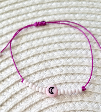 Pulsera realizada con hilo morado, con cierre de macramé y mini bolas de rocalla en tono blanco roto mate.   Póntela en la muñeca izquierda para atraer energía positiva a tu vida.